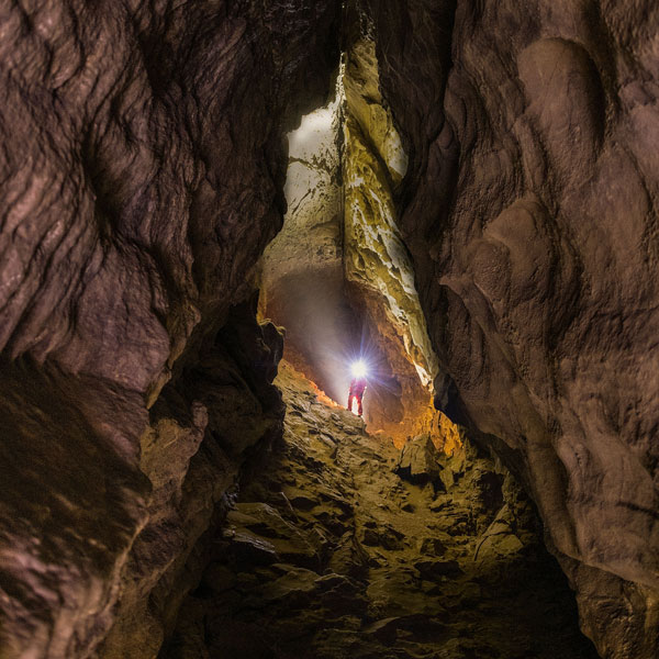 Caver standing in the Grand Gallery of Rat's Nest Cave near Canmore