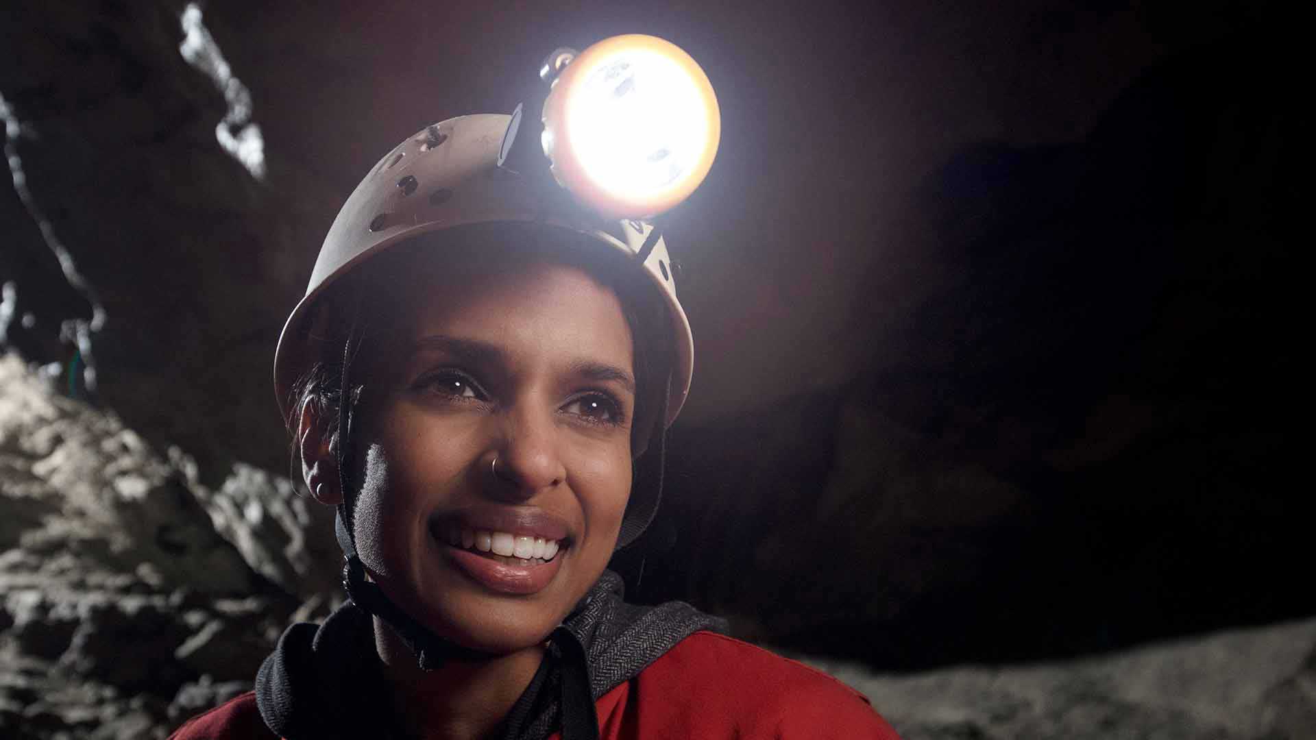 Happy female caver on the Explorer Tour wearing a helmet, light and coveralls.